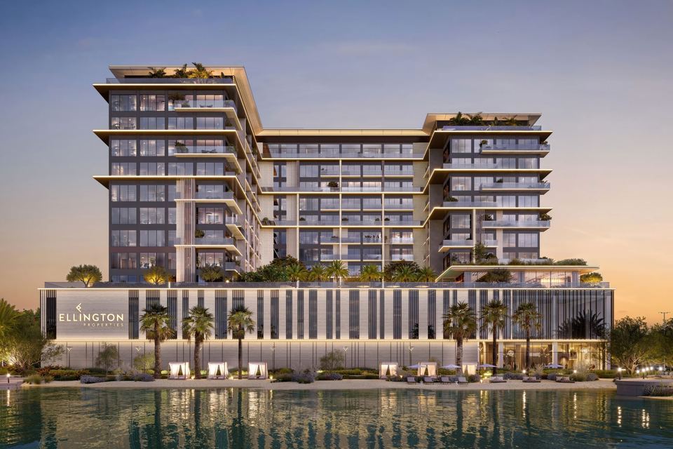 Everly Place tower at dusk seen across the lagoon, with the podium and palm-lined waterfront